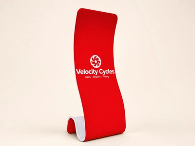 Red stretch fabric snake stand for Velocity Cycles curving upright against a plain backdrop