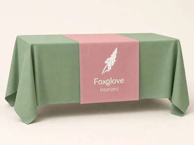 Pink table runner for Foxglove Interiors over a sage green tablecloth against a plain backdrop