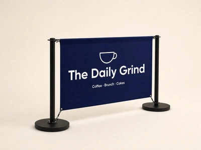 Economy cafe barrier with navy The Daily Grind banner and black posts on a plain studio backdrop