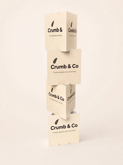 Stacked cardboard totem display for Crumb & Co bakery on a plain studio backdrop