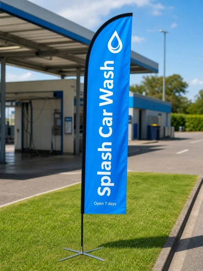 Blue feather flag for Splash Car Wash on the grass verge beside a petrol station forecourt